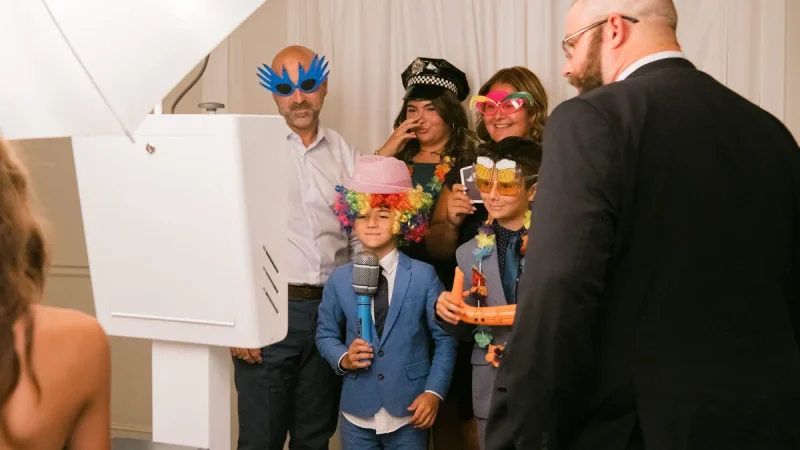 Family wearing wigs and novelty glasses at the Sound of Harmony photo booth during a Niagara wedding reception