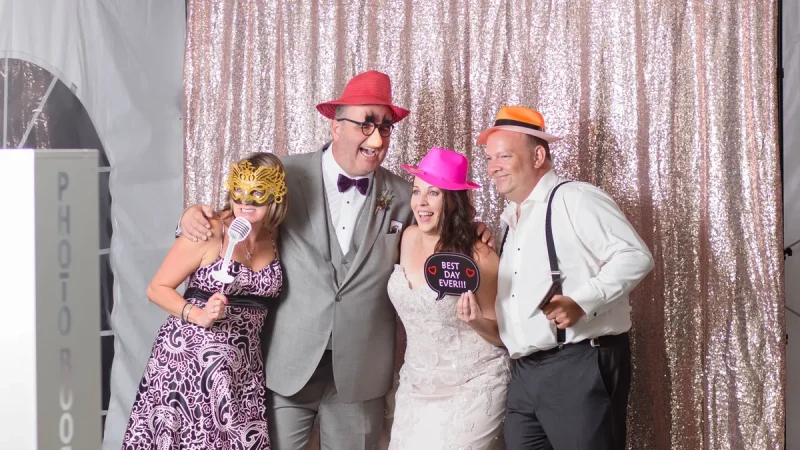 Bride and guests posing with hats and props at the Sound of Harmony photo booth during a Niagara wedding